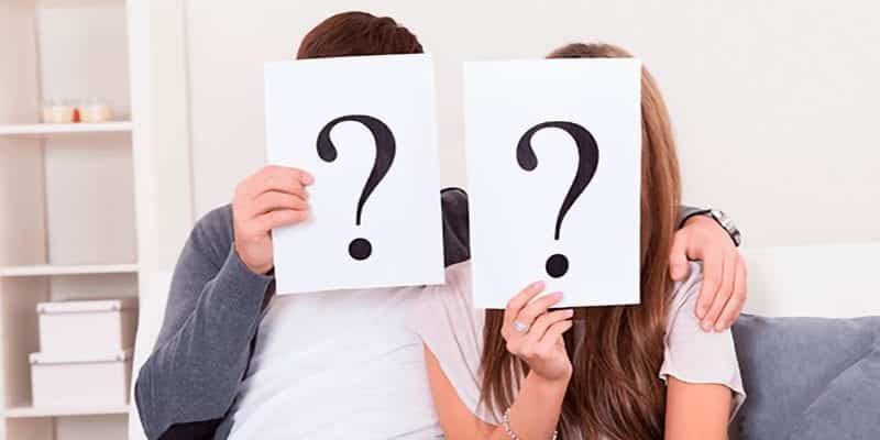 Couple on Couch With Question Marks In Front of Faces Couple on Couch With Question Marks In Front of Faces
