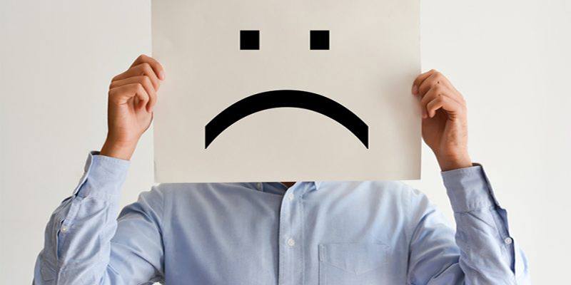 Business Man With Sad Face on Paper Covering His Face